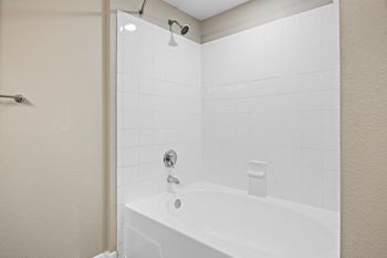 A white bathtub with a shower head above it.